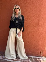 Pantalón palazzo de seda color beige, de corte sastrero y tiro alto.