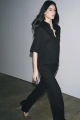 Camisa negra de manga corta confeccionada en hilatura con lyocell y ramio, con cuello solapa, bajo recto y cierre frontal con botones.