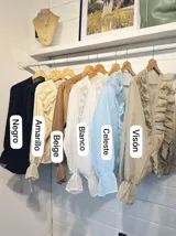 Camisa celeste de organza con volados en el frente y mangas largas abullonadas.