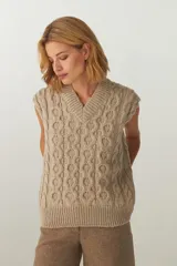 Chaleco de punto color crema con diseño trenzado y cuello en V.