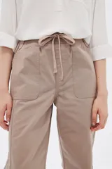 Pantalón de algodón color beige, de corte recto y tiro medio, con bolsillos laterales y cintura con cordón ajustable.