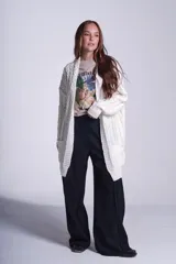 Saco tejido color crema con diseño de ochos y bolsillos frontales.