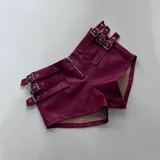 Short de cuero sintético color bordó con cierre frontal y múltiples correas con hebillas metálicas.