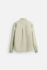 Camisa color arena de lino con cuello abotonado, manga larga con puños abotonados, corte regular y bajo con aberturas laterales.