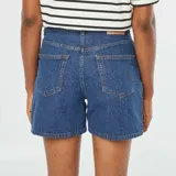 Short de jean azul oscuro, tiro alto, con corte recto y largo hasta medio muslo.