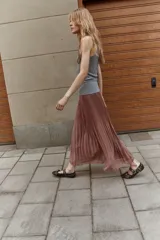 Pollera larga plisada color marrón, de tiro alto con elástico fino en la cintura y bajo sobrehilado con vuelo.