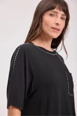 Remera negra de mangas cortas con cuello redondo y bolsillo en el pecho. Detalles de tachas plateadas en cuello, mangas y bolsillo.