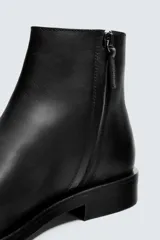 Bota de cuero negra con cierre de cremallera lateral, plantilla de cuero, horma cuadrada y tacón bajo.