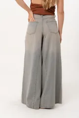 Jean súper campana de tiro alto, color celeste vintage, con pierna extra ancha y caída fluida. Cuenta con bolsillos delanteros y traseros, y cierre frontal con cremallera y botón metálico.