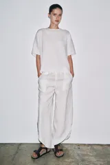 Top de lino color blanco, con cuello redondo y mangas cortas. Detalle de abertura en la espalda ajustable con lazadas.