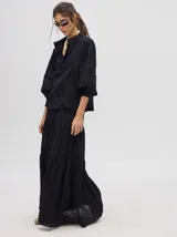 Camisa de broderie de algodón color negro, con cuello mao y cierre de cuatro botones. Presenta mangas abullonadas y galones con transparencias en la parte delantera y mangas.