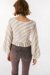 Blusa blanca de lino con escote en V, mangas largas abullonadas y frunce central.