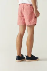 Short de baño estampado con hojas de palmera en tonos azul y verde. Tiene cintura elástica con cordón ajustable, dos bolsillos laterales y uno trasero.