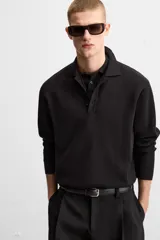 Polo de manga larga color negro, de punto tejido en hilatura de algodón, corte relaxed fit, con cuello solapa y cierre frontal de botonadura.