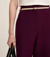 Pantalón de vestir azul marino, de corte zanahoria, con cinturón fino negro con hebilla dorada.