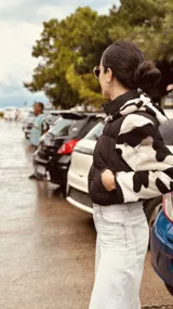 Campera puffer cropped negra con mangas y capucha de polar estampado con diseño geométrico en tonos beige, marrón y negro.