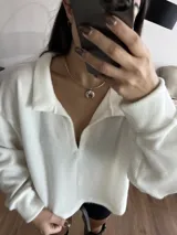 Buzo blanco de tejido de punto con cuello polo y mangas largas.