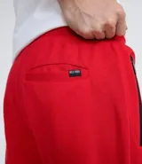 Pantalón jogger rojo de algodón con ajuste en los tobillos, bolsillos laterales con cierre y cintura elástica.