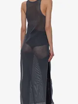 Vestido maxi de malla gris oscuro, sin mangas y con cuello redondo, caracterizado por su transparencia y aberturas laterales altas. Presenta un detalle de placa metálica cromada en el pecho.