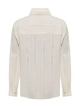 Blusa color crema de manga larga con cuello clásico y cierre frontal con botones. Presenta detalles de calado vertical en el frente y las mangas.