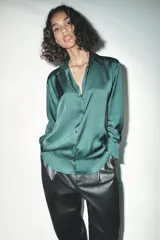 Camisa azul marino de satén con cuello solapa, escote en pico y mangas largas con puños abotonados.