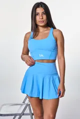Conjunto deportivo celeste compuesto por top corto con breteles anchos y falda corta tableada.