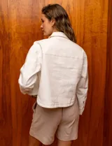 Campera de denim blanca con cuello con solapa, abertura central con botones metálicos y bolsillos delanteros.