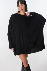 Sweater negro de punto con trenzas, corte holgado, mangas largas y bolsillos delanteros.