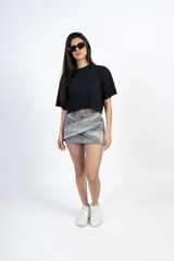 Minifalda gris de jean con diseño cruzado y tachas plateadas.