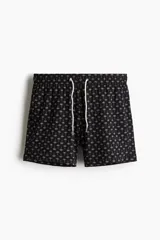 Traje de baño negro con estampado de palmeras blancas, con elástico y cordón en la cintura, bolsillos laterales y trasero con cierre autoadherente.