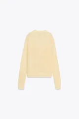 Jersey color crema de punto liso, con cuello redondo, tapeta de botones y manga larga.