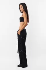 Pantalón negro de corte recto y tiro medio, con recortes en las piernas con detalle de vivo. Cintura con presillas y cinto correa con broche plástico incluido.