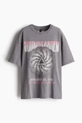 Remera gris de corte amplio con estampado del logo de la banda Soundgarden y la fecha de un concierto.