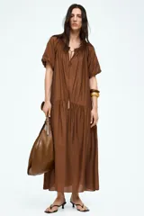 Vestido largo marrón con escote cuadrado y cordón ajustable con borlas. Mangas cortas abullonadas con forro y ribete elástico oculto.