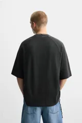 Camiseta negra de corte relaxed fit, cuello redondo y mangas cortas. Tejido de punto con textura acanalada y efecto lavado.