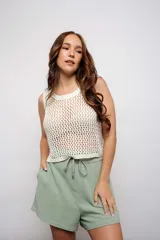 Blusa de tejido de punto calado color crema, sin mangas y corte crop.