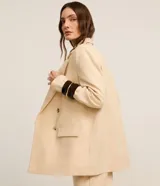 Blazer oversized color beige confeccionado en viscolino, con solapas en el cuello, botones delanteros y solapas delanteras que simulan bolsillos.