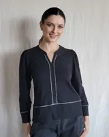 Remera negra de mangas largas con cuello en V y detalles de pespuntes blancos.