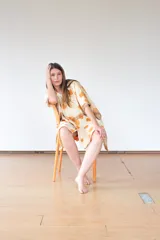 Capa de lana color crudo con estampado de hojas de eucalipto en tonos naranja y marrón. Tiene cierre con broches a presión en el escote y ojales metálicos con cintas para anudar en los laterales.