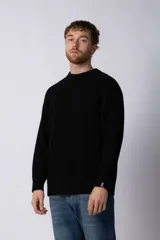 Sweater marrón de punto con cuello redondo y mangas largas raglán. Tejido grueso con textura acanalada. Corte holgado.