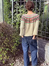 Sweater tejido a mano con hilo 100% algodón color beige, con cuello redondo y mangas largas. Presenta un diseño geométrico en el área del pecho en colores rosa, verde y marrón.