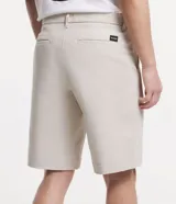 Bermuda de hombre, modelo loose con corte de sastrería, confeccionada en sarga de algodón y elastano. Color beige claro, con cierre de botón y cremallera, bolsillos y bajo ancho.