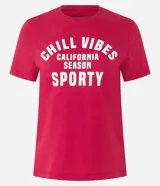 Remera baby look roja de algodón con estampa frontal con la frase "Chill Vibes California Season Sporty" en color blanco.