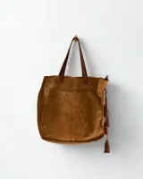 Cartera marrón de cuero con flecos y doble asa circular metálica.