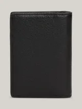 Billetera plegable de cuero negro con paneles de diferentes texturas y detalle de logo de Tommy Hilfiger en el frente.