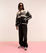Campera masculina de cuero sintético, modelo boxy, con cuello inglés, manga larga, estampa lettering, detalles contrastantes, bolsillos y cierre por cremallera.