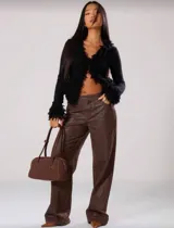 Cardigan negro de punto ajustado al cuerpo, con mangas largas y cuello en V. Presenta un detalle de flecos texturizados a lo largo del borde frontal y en los puños.