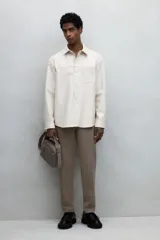 Pantalón jogger de vestir color beige, corte slim fit, con cintura elástica ajustable con cordón, pliegues delanteros y traseros, bolsillos laterales al bies y bolsillos traseros insertados.