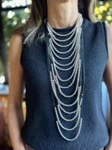 Collar largo de múltiples hilos con cuentas plateadas y cordones negros.