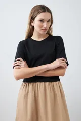 Vestido midi de corte recto, con top negro de mangas cortas y falda color beige.